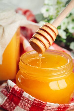 Honey background. Sweet honey in glass jar on wooden background. creative photo.の写真素材