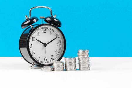 Alarm clock and money coins on the table. creative photo.の写真素材