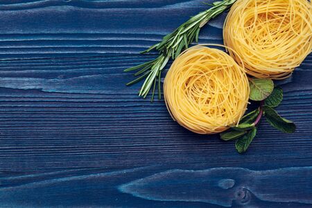 raw dry italian pasta fettuccine on blue wooden backgroundの写真素材