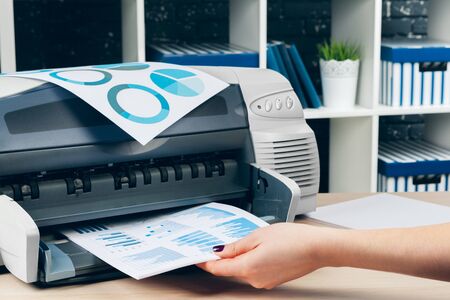 Female secretary making photocopies on xerox machine in office. Close up.