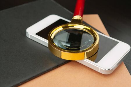 Conceptual image depicting conducting an online search for information with a magnifying glass. Close up.の写真素材