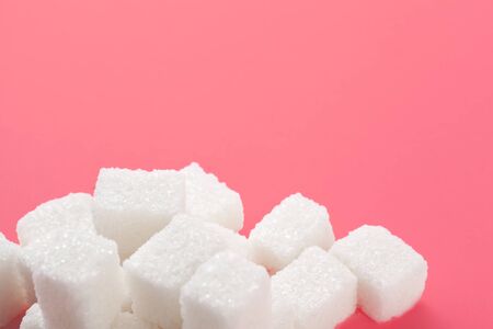 Cubes of sugar on a pink background. Empty space for copying text. Close up.