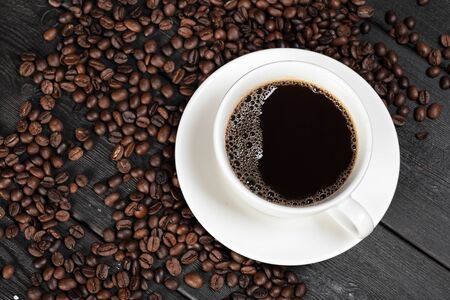 Cup of coffee and beans on wooden background. Close up.