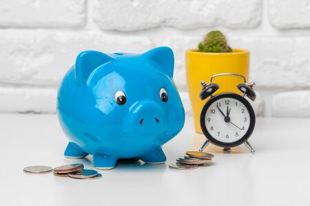 Piggy bank save coin and alarm clock, time and money concept. Close up.の写真素材