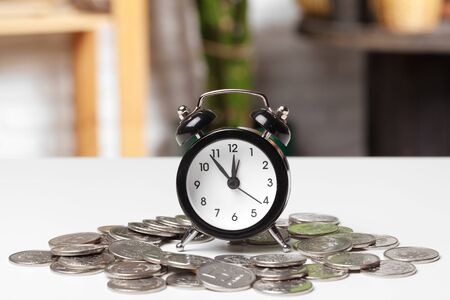 Alarm clock and money coins on the table. Close up.