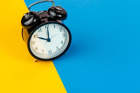 Black alarm clock on color block yellow and blue backgroundの写真素材