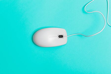 Computer mouse on a turquoise paper background. Close up.