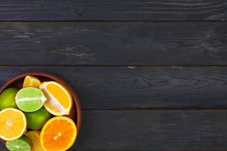 Bowl of citrus fruits on black wooden background, top view. Close up.の写真素材