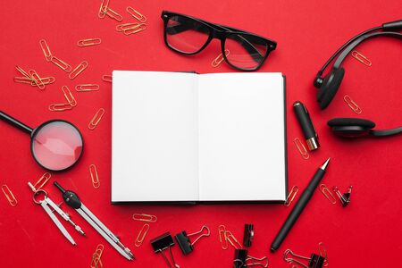 Flat lay, top view office table desk. Workspace with blank note book, office supplies on red background. Close up.の写真素材