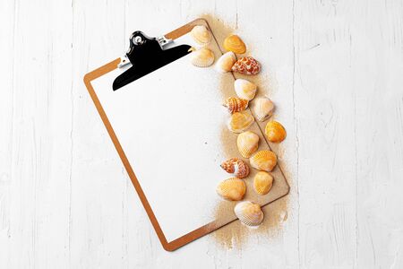 Clipboard with sea shells on wooden table close up, copy spaceの写真素材