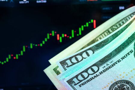 Dollars in front of a monitor with a price chart. Forex and trading.の写真素材