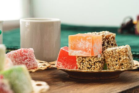 Close up of a little plate with turkish sweets and cup of espresso on wooden table