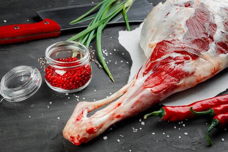 Raw lamb leg on black stone background, close upの写真素材