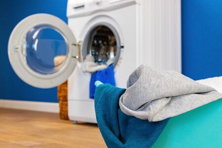 Washing machine with laundry on blue wall backgroundの写真素材