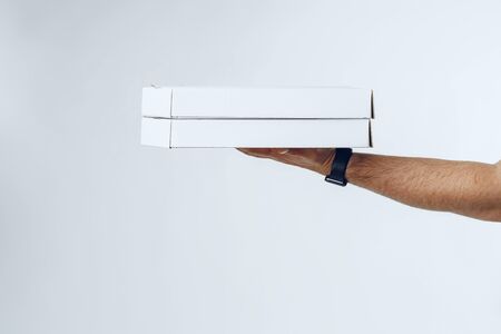 Courier hands giving packed food delivery close up against grey backgroundの写真素材