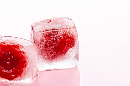 Raspberry ice cubes on pink glossy backgroundの写真素材