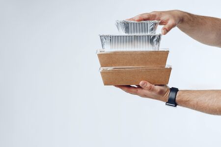Courier hands giving packed food delivery close up against grey background