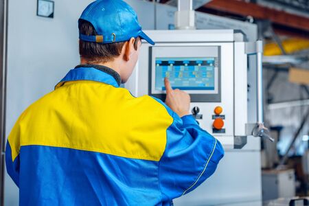 Man worker in manufacturing plant at cable factory machine control computer panel, close up