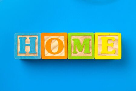 Home. Wooden colorful alphabet blocks on blue background, flat lay, top view.の写真素材