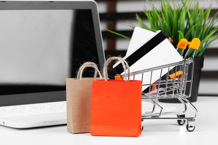 Online shopping concept. Shopping cart, laptop on the deskの写真素材