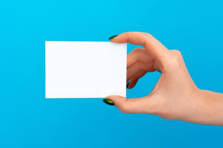 Woman hand holding blank card on blue background, close up.の写真素材