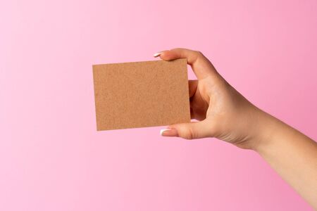 Woman hand showing blank business card on pink background. Close up.の写真素材