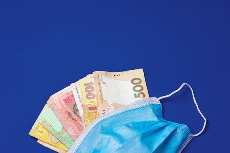 Medical face mask and Ukrainian hryvnia banknotes on blueの写真素材