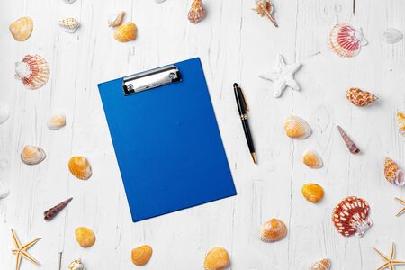 Clipboard with sea shells on wooden table close up, copy spaceの写真素材