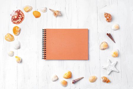 Open notepad with sea shells on white wooden backgroundの写真素材