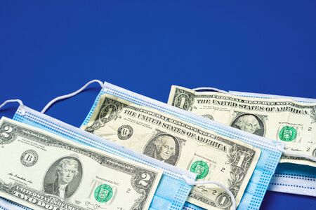 Close up of medical protective masks and american dollar banknotes on blue background