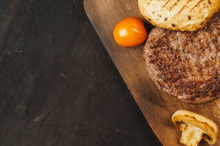 Grilled burger cutlet with a bun on wooden boardの写真素材