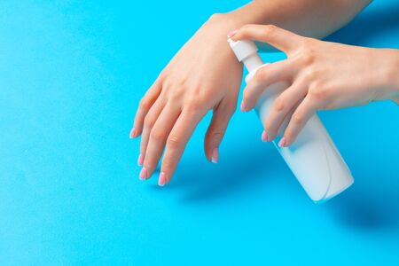 Female hand holding skincare product bottle on blue