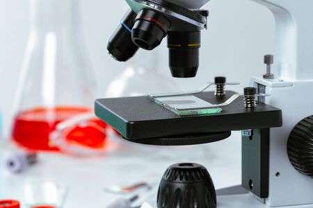 Close up photo of a microscope lenses examining glass sample in laboratoryの写真素材