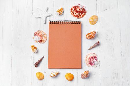 Open notepad with sea shells on white wooden backgroundの写真素材