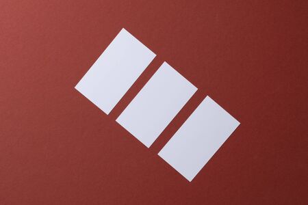 Blank white business cards on burgundy paper backgroundの写真素材