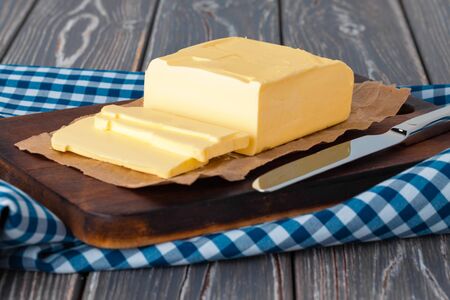 Wooden board with butter on blue checkered napkinの写真素材