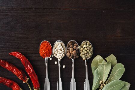Spices in spoons on dark wooden background top viewの写真素材