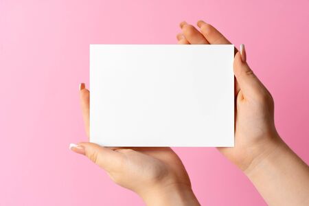 Woman hand showing blank business card on pink background.の写真素材