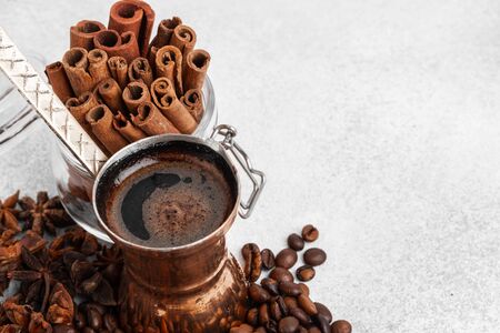 Close up of copper coffee turk on light textured surface with roasted beansの写真素材