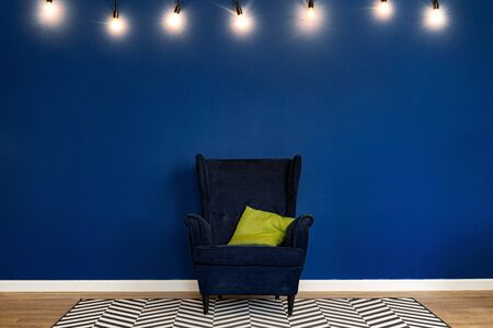 Dark blue arm-chair against blue wall in modern living roomの写真素材