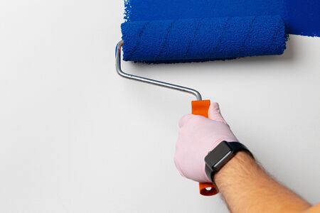 Gloved male hand painting wall into classic blue colorの写真素材