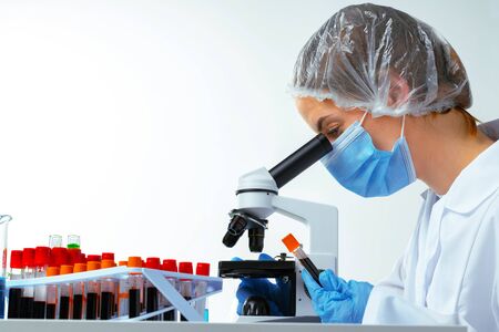Woman scientist looking through a microscope in laboratory. Scientific research