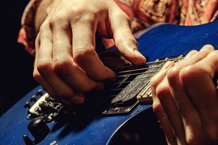 Close up of male hand playing electric guitar in the darkの写真素材