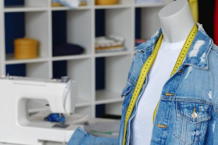 Plastic mannequin wearing shirt and denim jacket with yellow measuring tape. Seamstress officeの写真素材