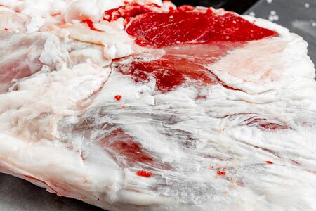 Raw lamb leg on black stone background, close upの写真素材