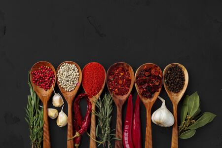 Various exotic spices in wooden spoons on dark backgroundの写真素材