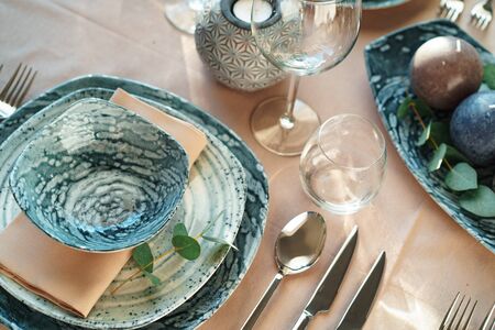 Beautiful elegant table setting with green stylish dishware and silver cutlery close up