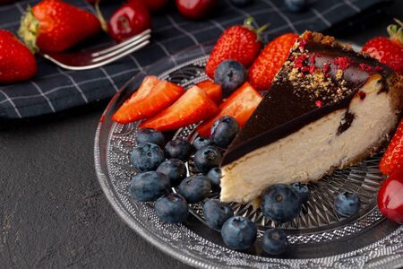 Piece of cheesecake with chocolate top and fresh berriesの写真素材