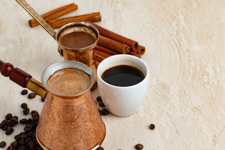 Close up of copper coffee turk on light textured surface with roasted beansの写真素材