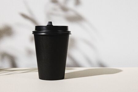 Takeout coffee cup with foliage shadows, copy spaceの写真素材